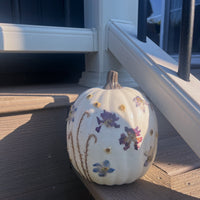 pressed flowers attached to a white pumpkin on the side of the stairs outside a house