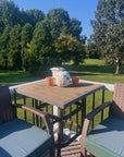 an outdoor porch with chairs and a table that has a white pumpkin with colorful pressed flowers on it and other decor with trees in the background