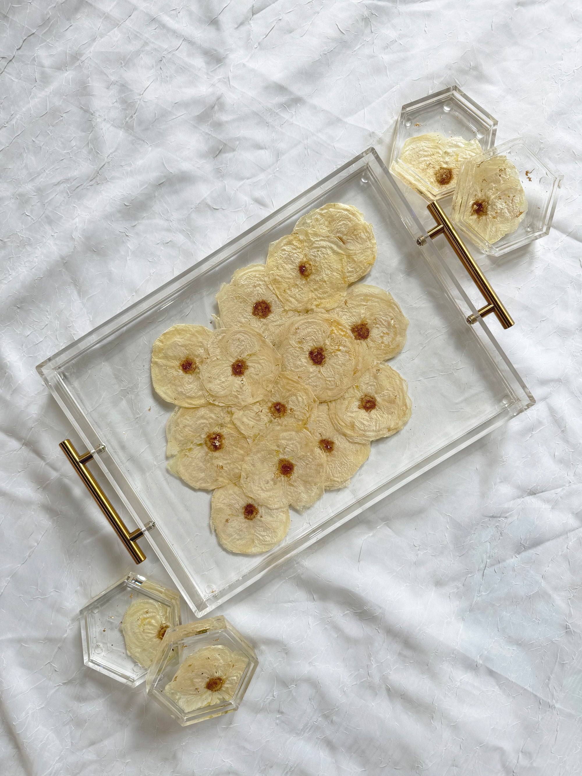 Rectangle resin tray with gold handles and four hexagon resin coasters, featuring pressed white roses and silver metallic flakes on a white background.