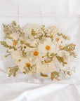 A white and green wedding bouquet pressed and preserved in a serving tray with gold handles. 