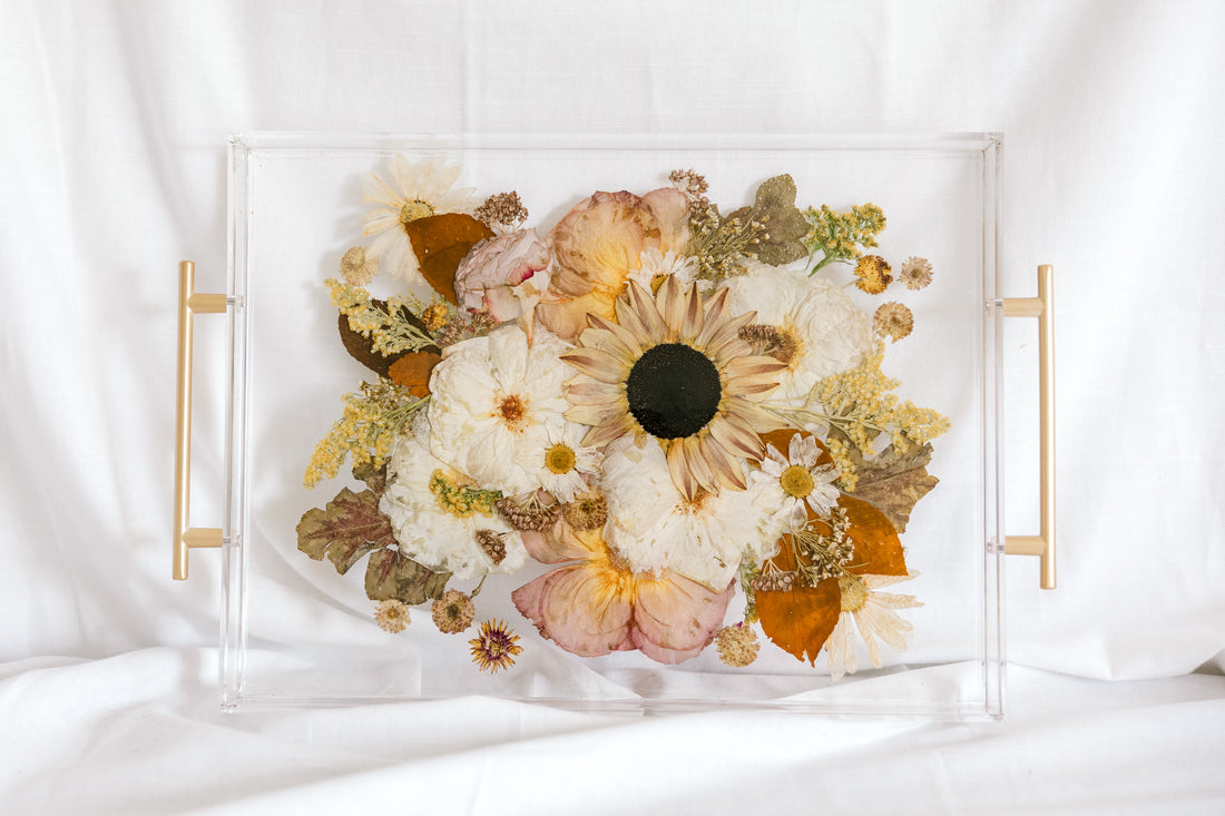 A fall-toned wedding bouquet preserved in a resin serving tray with gold handles. 