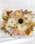 A fall-toned wedding bouquet preserved in a resin serving tray with gold handles. 