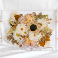 A fall-toned wedding bouquet preserved in a resin serving tray with gold handles. 