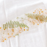 White, green, and yellow flowers pressed and preserved in a display trade made out of resin. 