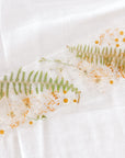 White, green, and yellow flowers pressed and preserved in a display trade made out of resin. 