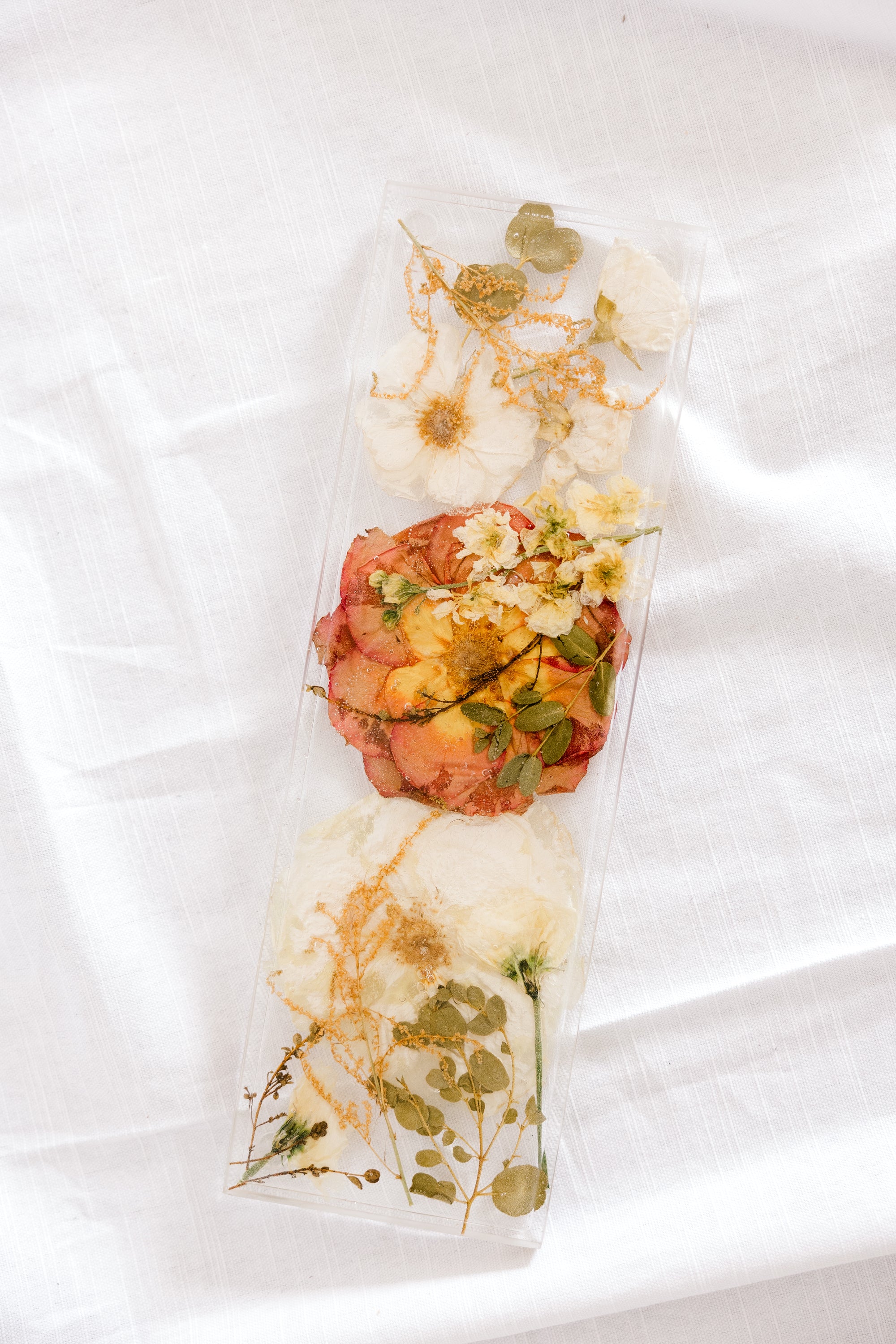 White and orange wedding flowers preserved in resin as a display tray. 