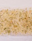 A resin serving tray with green leaves, white flowers, and gold metallic flakes are designed like confetti. The tray has black handles and is against a white background. 