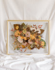 A fall-toned wedding bouquet that has been pressed into a gold wood frame as a bouquet preservation service.