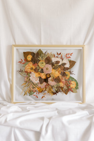 A fall-toned wedding bouquet that has been pressed into a gold wood frame as a bouquet preservation service.