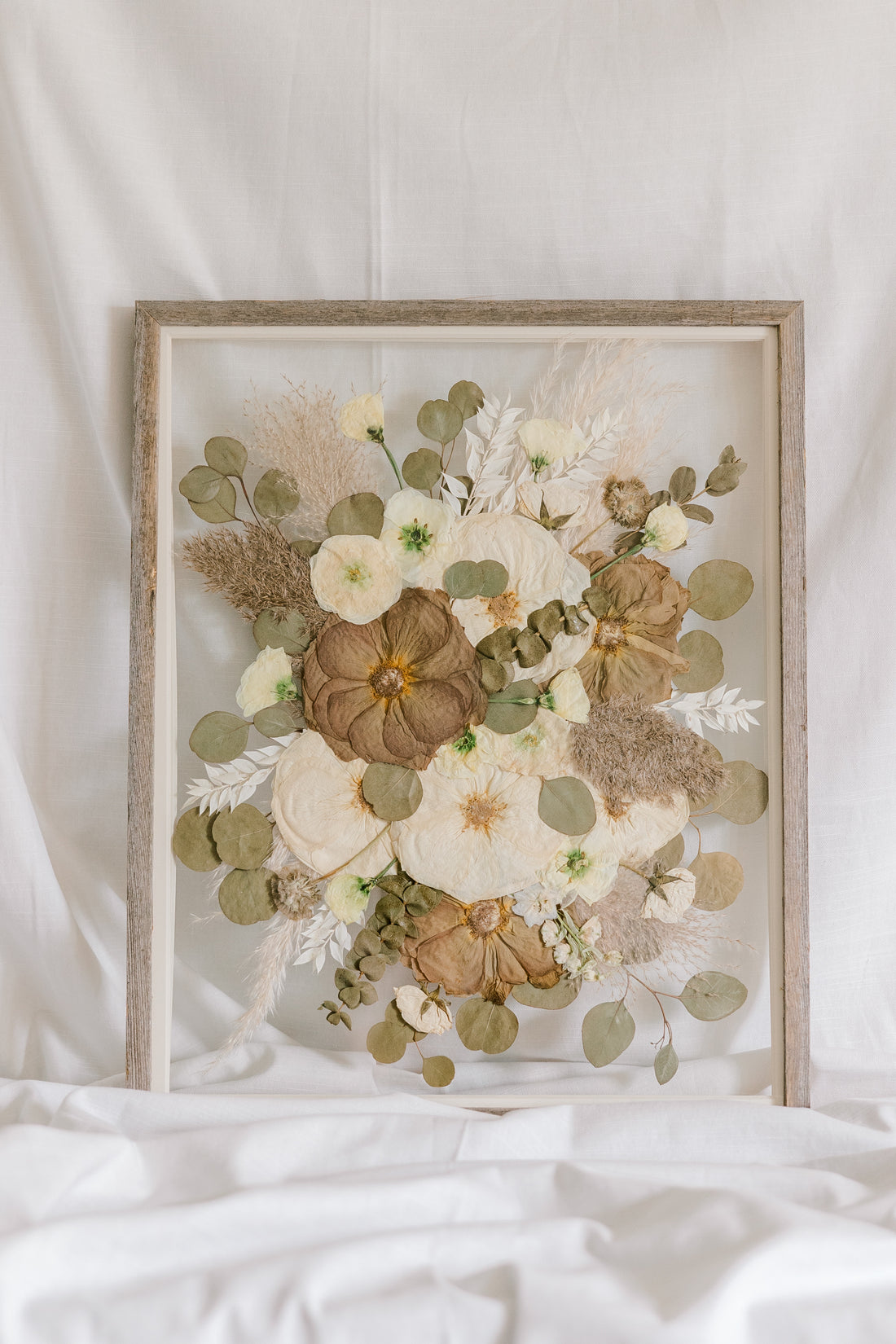 A fall-toned pressed wedding bouquet in a barn wood frame. 