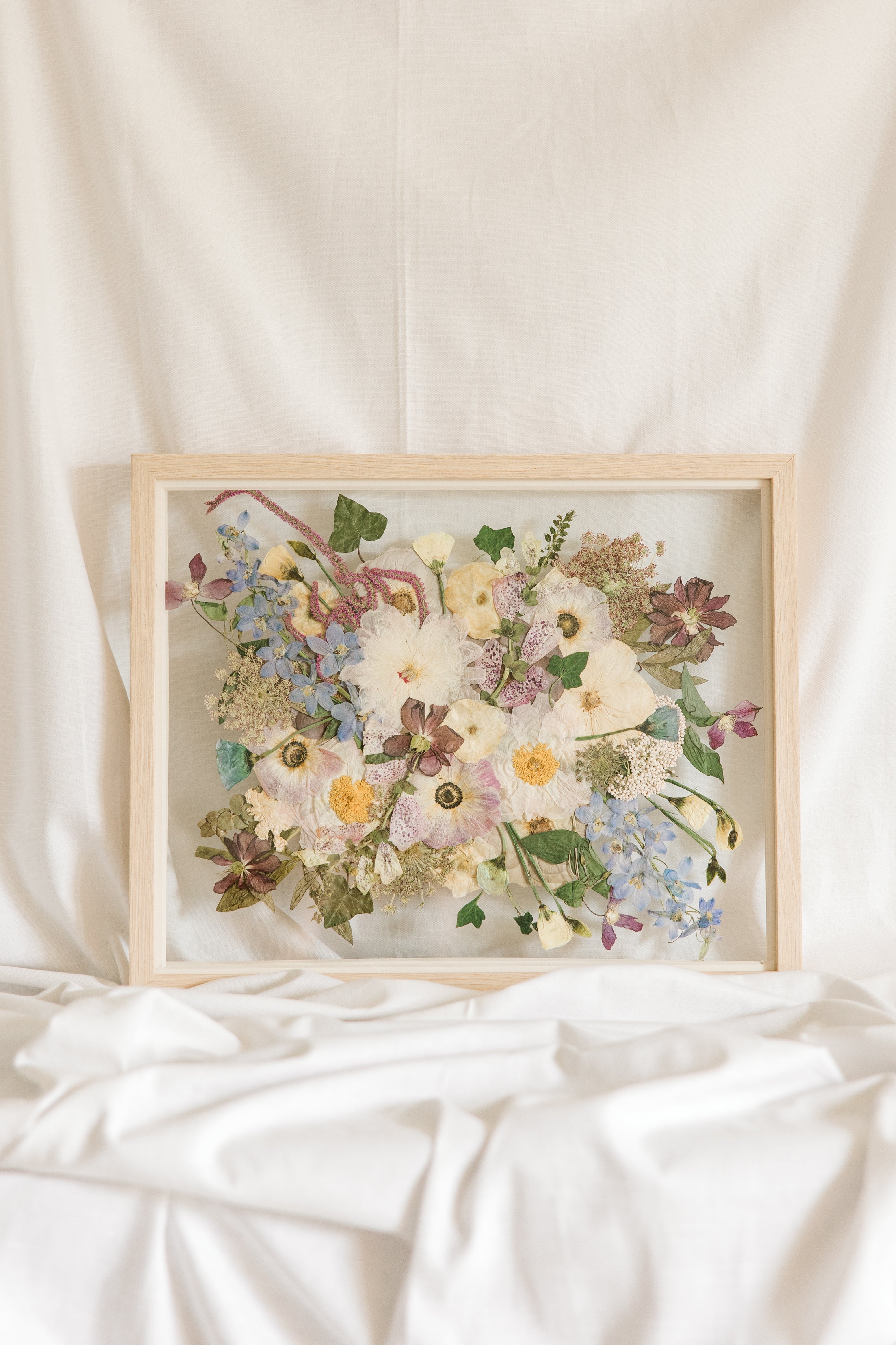 Wedding bouquet pressed and preserved in a floating frame made of natural colored wood. 