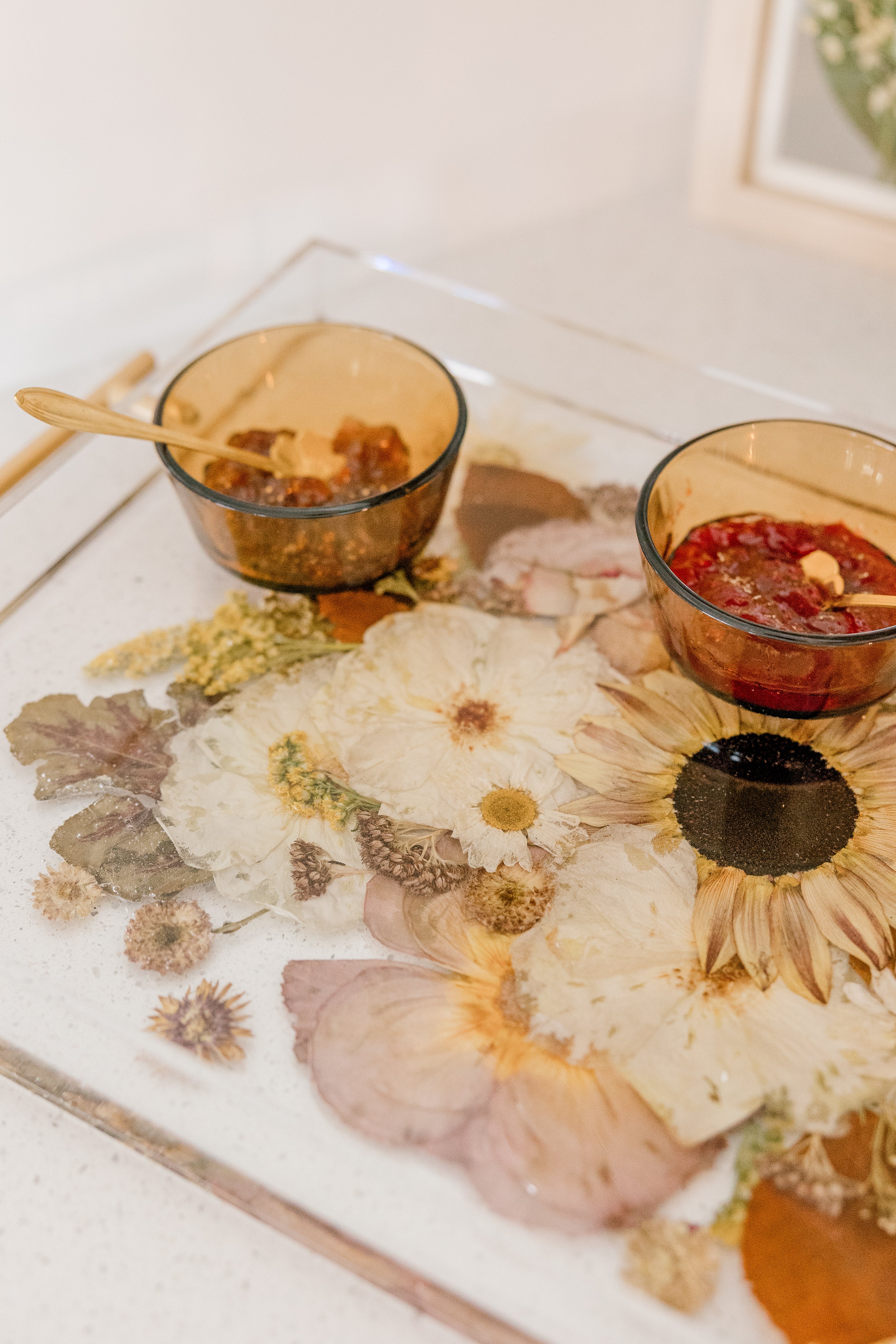 A close-up view of a resin serving tray with fall-toned flowers and gold handles. Flower preservation in the forms of function.