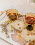 A close-up view of a resin serving tray with fall-toned flowers and gold handles. Flower preservation in the forms of function.