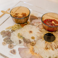 A close-up view of a resin serving tray with fall-toned flowers and gold handles. Flower preservation in the forms of function.