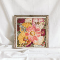 A colorful pressed flower arrangement in a barnwood frame made by the Pressed Bouquet Shop. 