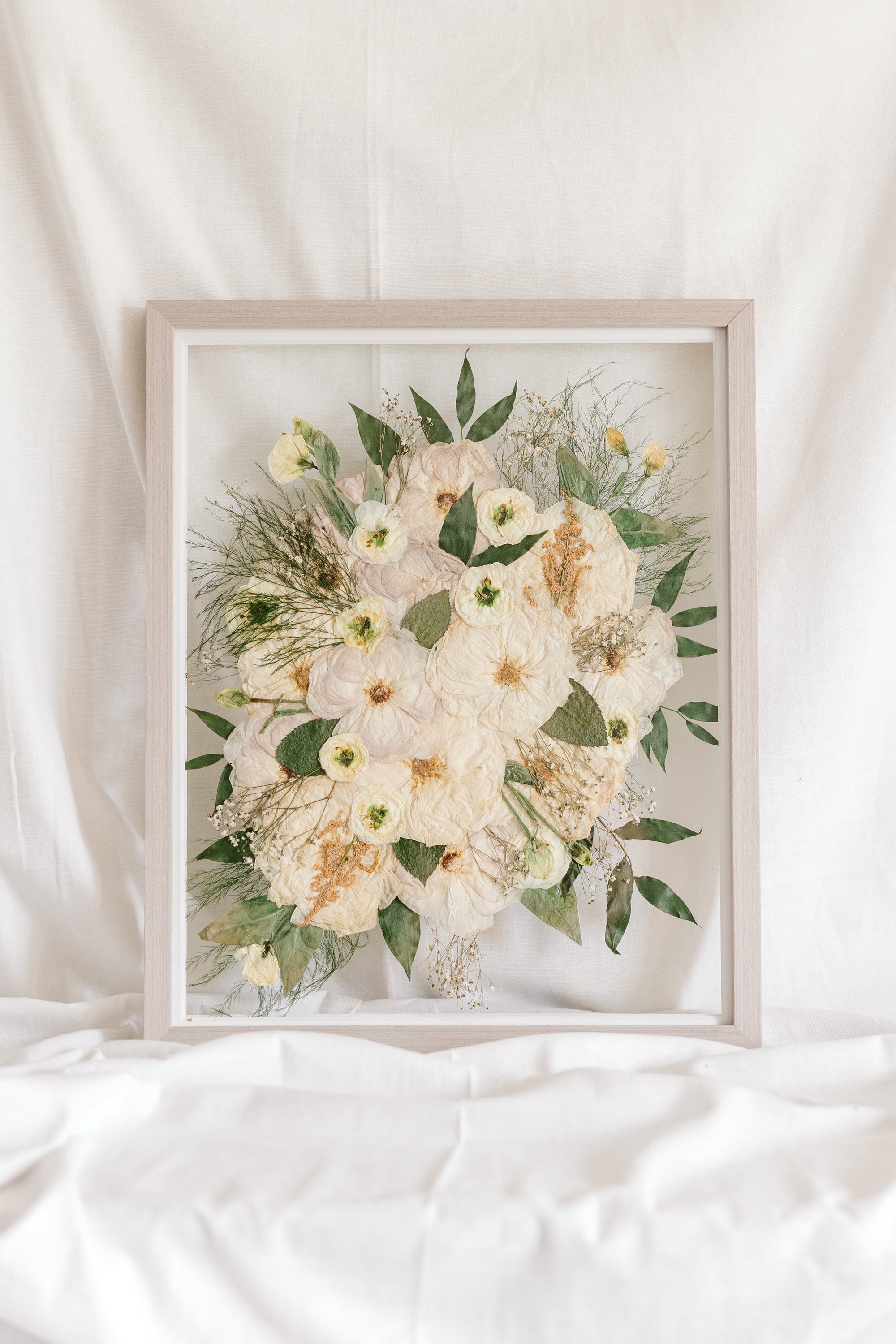 A custom preservation piece made from a wedding bouquet that can be hung on the wall as art. 