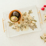 A bowl of avocados sitting on top of a preserved wedding bouquet in the shape of a serving tray with gold handles. 