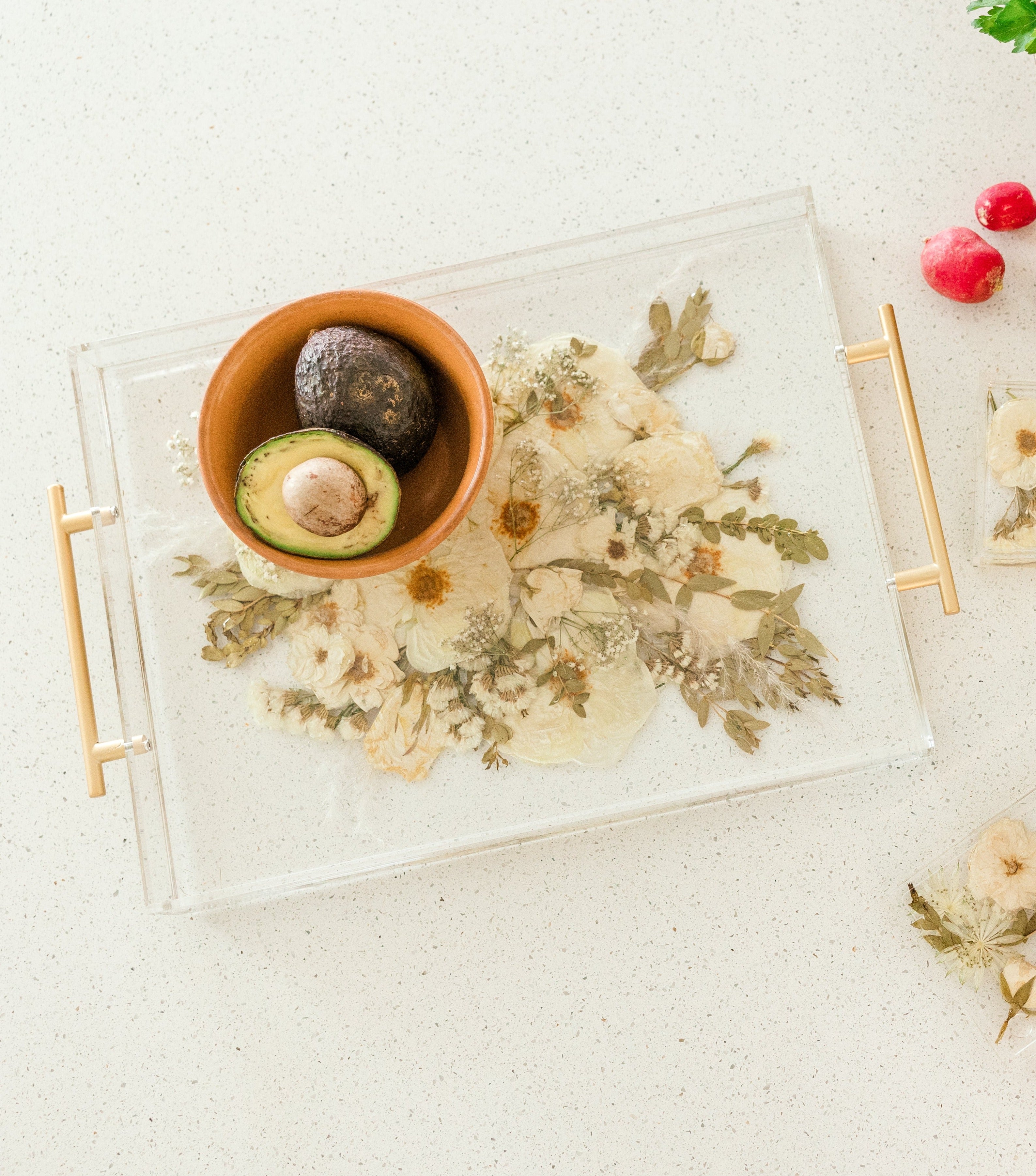 A bowl of avocados sitting on top of a preserved wedding bouquet in the shape of a serving tray with gold handles. 