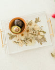 A bowl of avocados sitting on top of a preserved wedding bouquet in the shape of a serving tray with gold handles. 