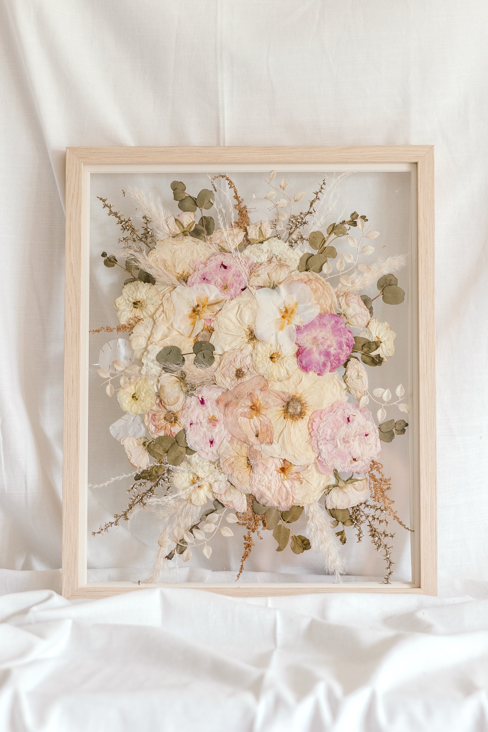 A beautiful wedding bouquet pressed and framed in a natural wood floating frame. 