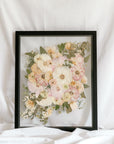 A wedding bouquet pressed and framed inside a black floating frame with a subtle wedding date detail added to the bottom right corner. 