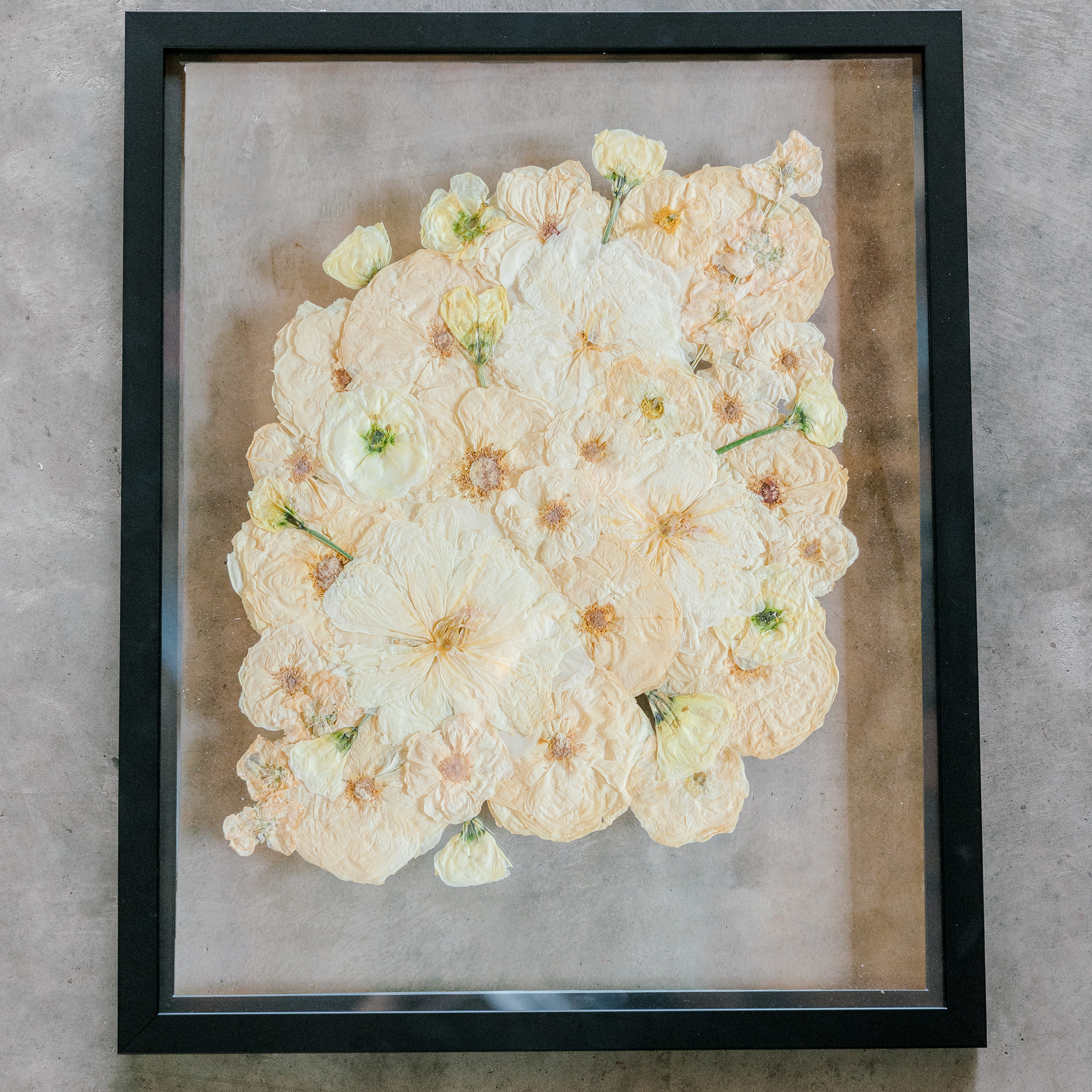 All white ball bouquet in black frame against concrete