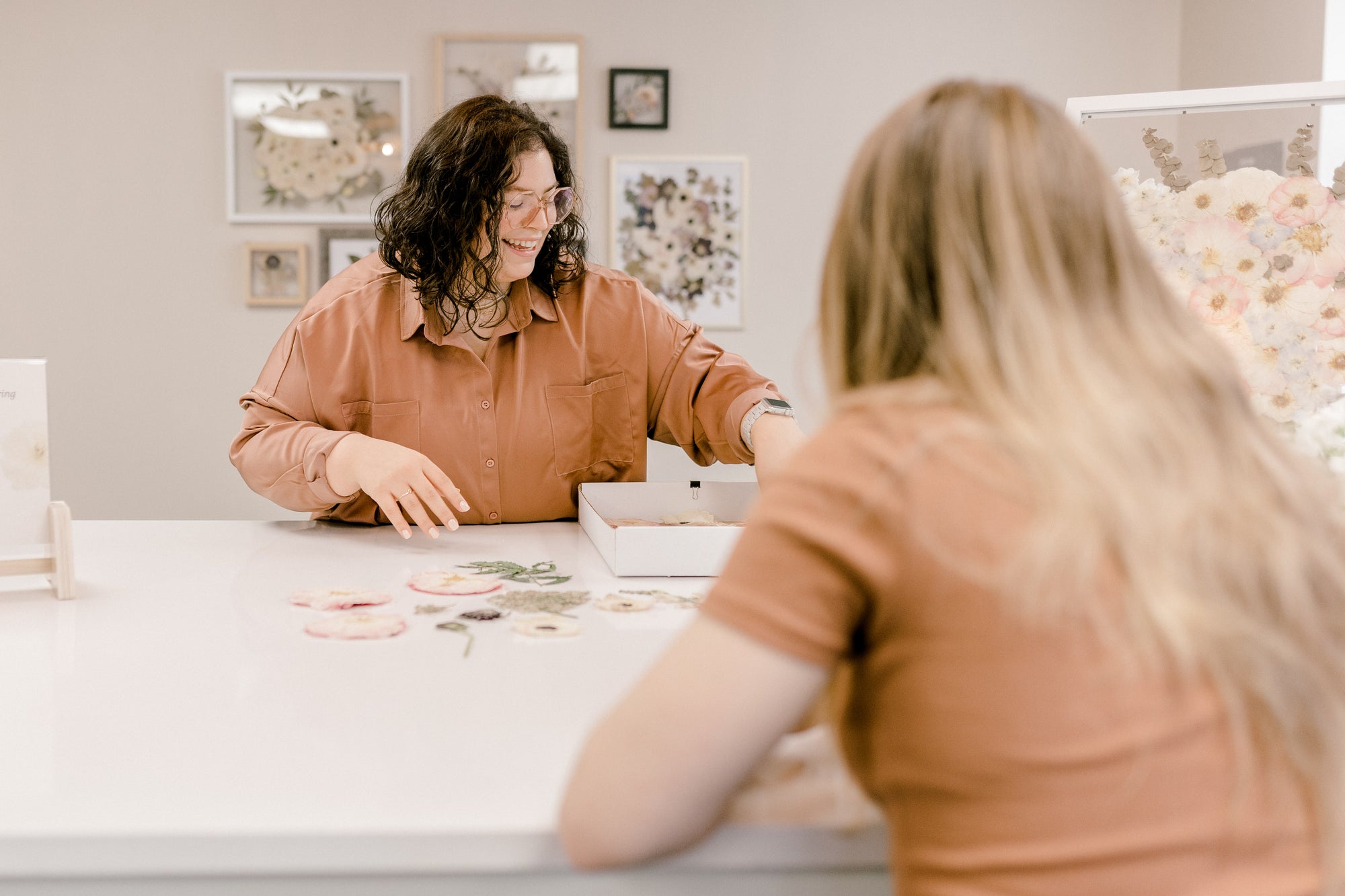 Element Preservation showing a client their pressed flowers during a design consult.