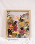 Pressed flowers are displayed as if they were growing from the ground in this gold wood floating frame.