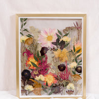 Pressed flowers are displayed as if they were growing from the ground in this gold wood floating frame.