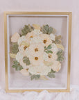 An all white bouquet of flowers has been pressed into a preserved piece of art. 