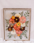 A vibrant pressed flower arrangement inside a barn wood frame. 