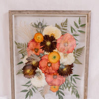 A vibrant pressed flower arrangement inside a barn wood frame. 