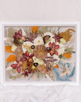 A full frame of pressed flowers from a wedding bouquet, a pressed boutonniere, and the ribbon that was wrapped around the stems of the wedding bouquet. 