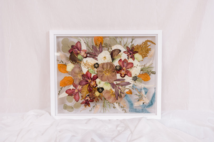 A full frame of pressed flowers from a wedding bouquet, a pressed boutonniere, and the ribbon that was wrapped around the stems of the wedding bouquet. 