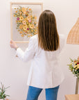 A woman holding a bright flower bouquet that has been pressed and put inside a frame. 