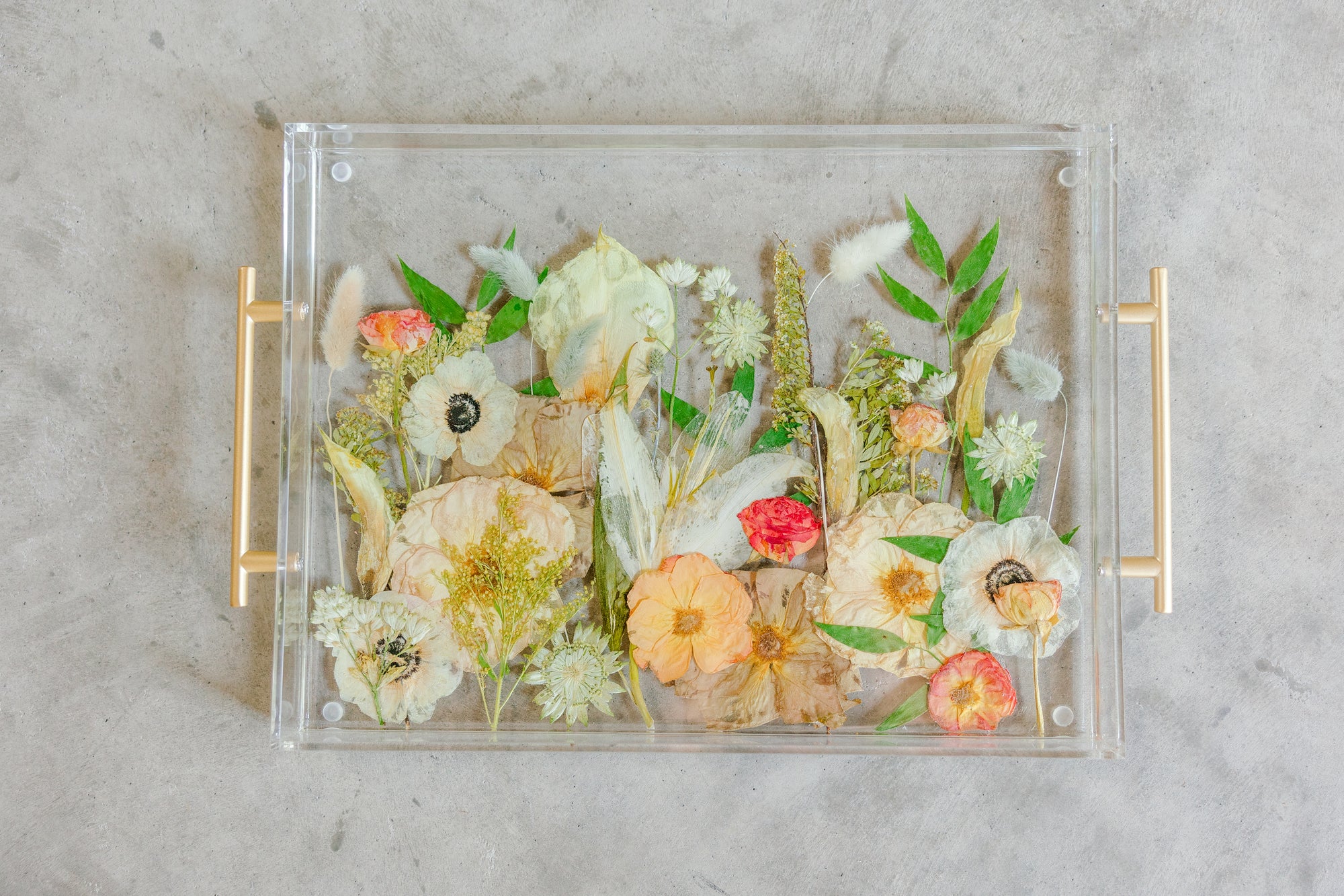 Pressed flower resin serving tray with gold handles in a field style design.