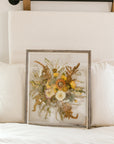 A fall pressed bouquet sitting against pillows on a bed.  