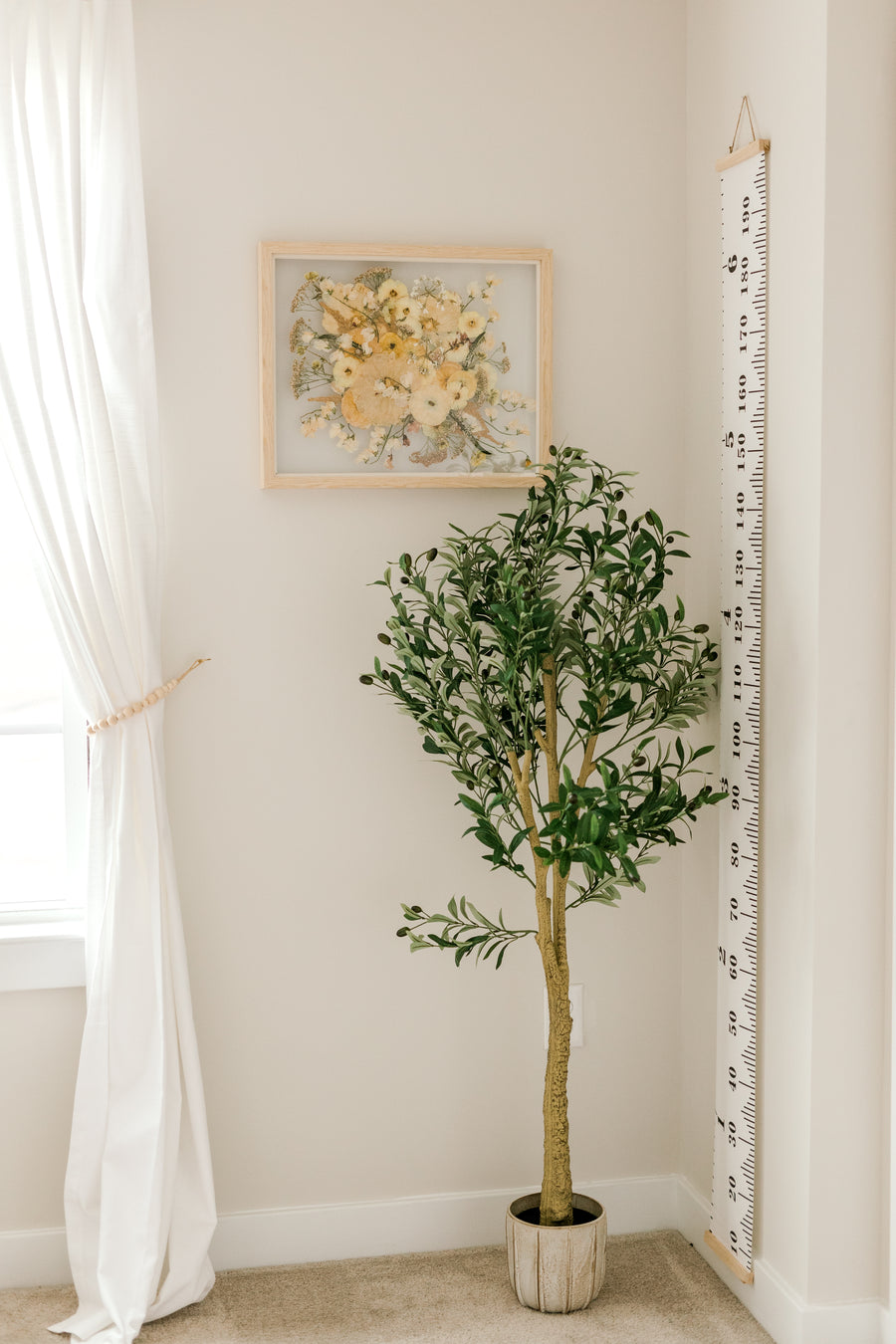A bouquet of flowers that have been pressed and framed are hung inside of a child's room on the wall. 
