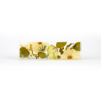A delicate design of white and green pressed florals in a resin display tray as a part of a wedding bouquet preservation order. 