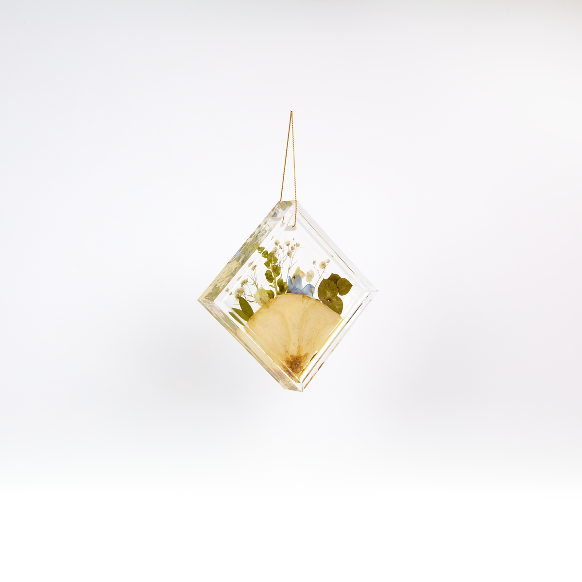 Pressed flower resin ornament in a diamond shape to as a part of a wedding bouquet preservation order. 