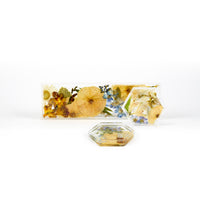 Pressed flower preservation of a wedding bouquet featuring blue, white, orange, and yellow toned preserved florals. A set of two floral resin ring dishes and a display tray. 