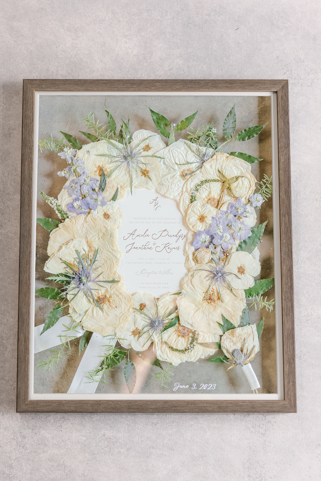 White, green, and blue florals pressed and preserved into a large wooden frame.