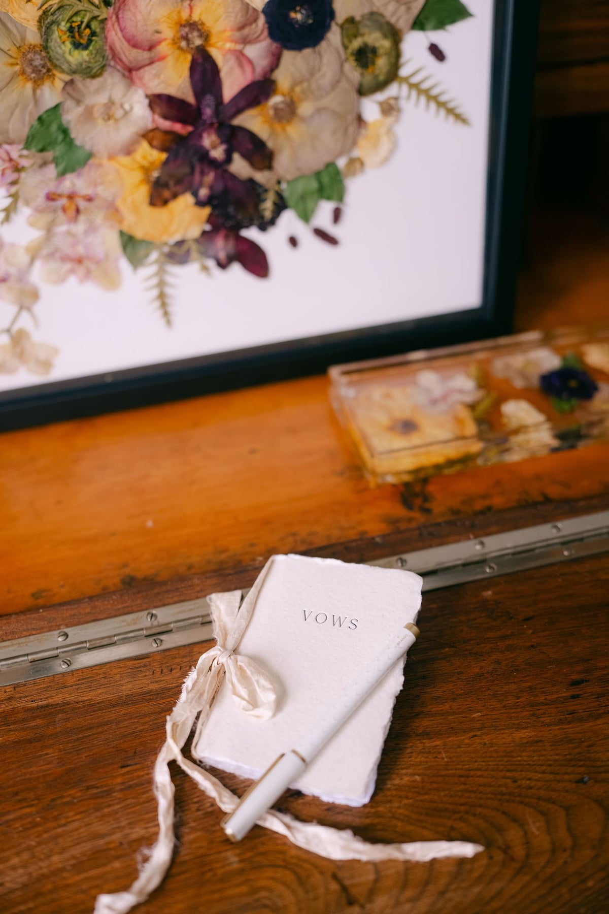 Wedding vow book from Element Marketplace, shown individually in front of pressed floral frame and resin tray