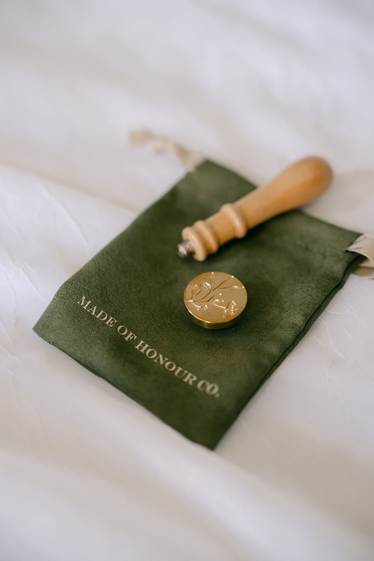 Brass wildflower wax seal stamp from Element Marketplace, shown separated on a cleaning cloth
