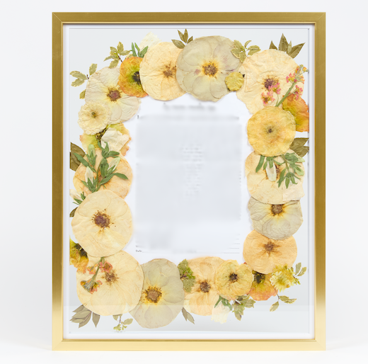 Pressed flowers surrounding a Ketubah in a gold frame