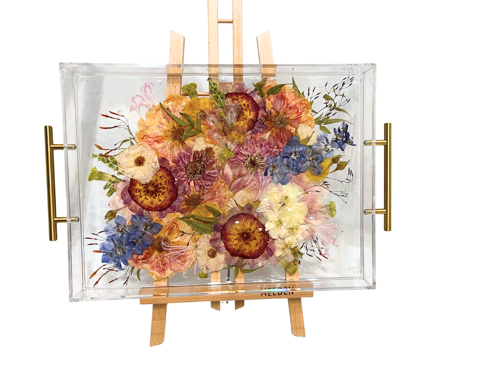 A pressed flower serving tray with colorful florals and gold handles. 