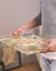 A man walks across the room holding his preserved wedding flower serving tray