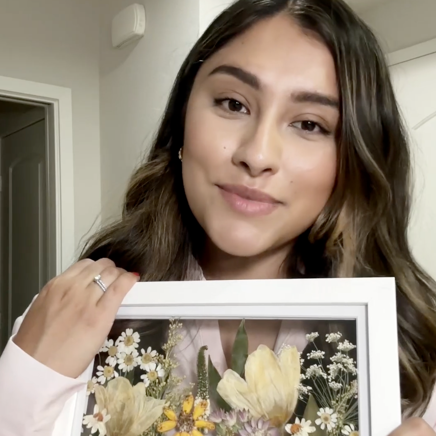 A woman explains her experience working with Element Design and shares some clips from her wedding day. She showcases her small bouquet preservation frame with dainty flowers pressed in field style. 