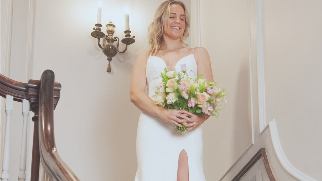 A bridal bouquet held by a bride on a staircase transforms into a pressed flower frame by the Pressed Bouquet Shop as the bride spins around. 
