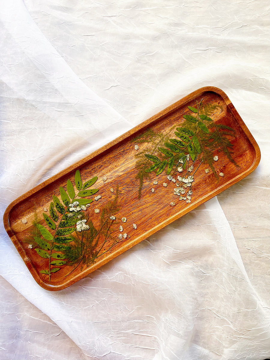 Pressed greenery and baby's breath on a wooden resin tray for home decor